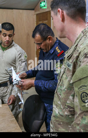 Un Irakien d'officier des opérations de la police fédérale (centre), de l'armée américaine le Capitaine Scott Sikora (à droite), un agent du personnel affecté au 1er Escadron, 73e Régiment de cavalerie, 2e Brigade Combat Team, 82e Division aéroportée, et U.S. Marine Cpl. Ali Mohammed (à gauche), un traducteur et un marin d'alimentation avec 3e Bataillon, 7e Régiment de Marines, marines à des fins spéciales Les Force-Crisis Response-Central Tâche Commande, inspecter un véhicule aérien sans pilote ISIL capturés au cours d'un échange de renseignement à l'engagement du chef du Centre d'opérations commun à Qayyarah Aérodrome de l'Ouest, de l'Iraq, le 9 février 2017. Déployées à l'appui de Banque D'Images