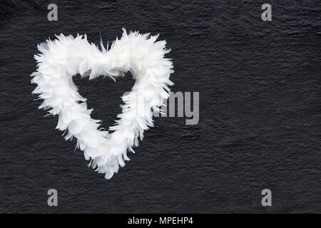 Coeur de plumes blanches sur la texture du mur gris anthracite copy space Banque D'Images
