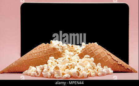Popcorn with digital tablet sur fond rose. Banque D'Images