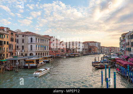 Coucher de soleil sur le Grand Canal de Riatlto Bridge, Venise, Vénétie, Italie avec un taxi d'eau et les gondoles amarrées Banque D'Images