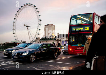 Les gens attendent pour le trafic sur le pont de Westminster sur la Tamise avec le London Eye ou roue du millénaire en début de soirée. Banque D'Images