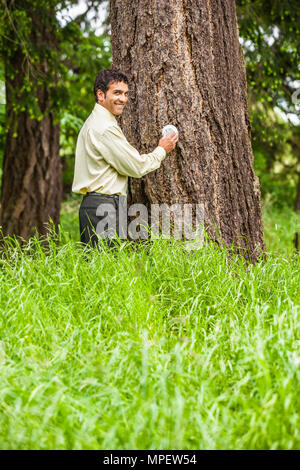 Plan conceptuel d'un businessman adjusting un thermostat relié à l'arbre à côté de lui. Illustrant le changement climatique / réchauffement climatique ou en tournant vers le bas Banque D'Images