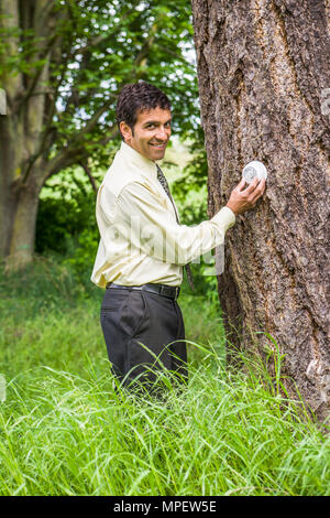 Plan conceptuel d'un businessman adjusting un thermostat relié à l'arbre à côté de lui. Illustrant le changement climatique / réchauffement climatique ou en tournant vers le bas Banque D'Images