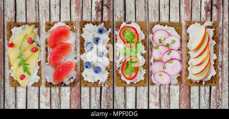 Sandwiches au fromage à la crème et les baies fraîches, fruits et légumes. Snack apéritif frais sain avec des biscottes. Banque D'Images