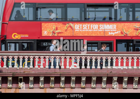 Les banlieusards marchant sur un pont sur la Tamise dans le centre de Londres au cours de l'heure de pointe du matin avec un double decker bus londres rouge derrière. Banque D'Images