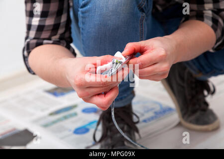 Close-up of a woman artist en jeans nettoie et prépare l'aérographe pour les travaux de peinture des murs. Banque D'Images