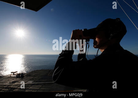 Océan Atlantique (10 avril 2017) -Maître de Manœuvre Seaman Kevin Thompson, de Syracuse, New York, affectés à l'unité Pre-Commissioning du Gerald R. Ford (CVN 78) Service du pont, utilise des jumelles pour analyser l'eau au cours de lookout watch sur vulture's row. L'avenir USS Gerald R. Ford (CVN 78) est en cours sur son moteur pour la première fois. La première classe de navire -- le premier porte-avions américain nouveau design en 40 ans -- va passer plusieurs jours à effectuer des essais en mer du constructeur, un test complet de bon nombre des principaux systèmes du navire et des technologies. Banque D'Images