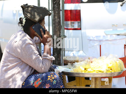 Yangon, Myanmar. 23 mai, 2018. Un vendeur des pourparlers sur un téléphone mobile à Yangon, Myanmar, le 23 mai 2018. L'utilisation du téléphone mobile a augmenté à plus de 110,43  % jusqu'à présent dans le Myanmar, selon le ministère des Transports et des communications le mardi. Credit : U Aung/Xinhua/Alamy Live News Banque D'Images