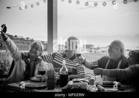 Groupe d'amis adultes âgés de hauts en train de dîner et faisant partie agréable moment dans le toit-terrasse piscine avec du vin et de l'alimentation. s'amuser pendant la s Banque D'Images
