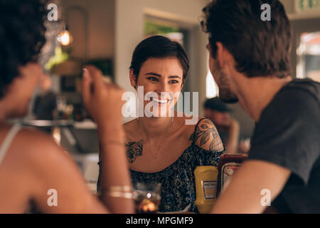 Belle jeune femme sourire et parler avec ses amis dans un café. Groupe de jeunes réunis au restaurant. Banque D'Images