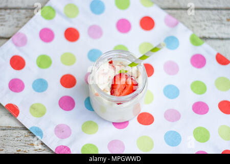 Pot de yaourt et de fraise avec chiffon multicolores sur table en bois Banque D'Images