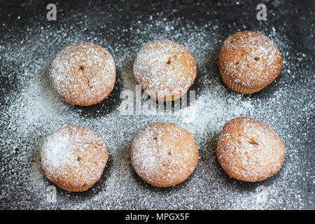 Muffins dans du sucre en poudre sur un tableau sombre Banque D'Images