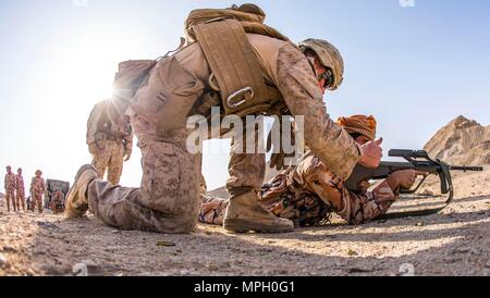 RABKUT, Oman (fév. 19, 2017) U.S. Marine Cpl. Zachery Personet, un fantassin avec un bataillon de l'entreprise, l'équipe d'atterrissage. Bn 1er, 4e, 11e de Marine Marine Expeditionary Unit, donne un coup de pouce à une armée royale d'Oman (RAO) soldat après avoir effacé un dysfonctionnement d'armes lors d'un tir de combat dans le cadre d'un projet de l'exercice Sea soldat, 19 février. Au cours de la gamme, les Marines formés la RAO soldats dans le Marine Corps techniques de l'adresse au tir debout, à genoux et sujet des positions de tir. 2017 Soldat de la mer est un annuel, exercice bilatéral mené avec l'Armée royale d'Oman conçus à des démons Banque D'Images