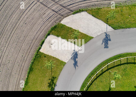 Résumé Vue aérienne de l'ombre de trois arbres debout au bord d'une courbe sur un chemin à côté d'un champ, faites avec drone Banque D'Images