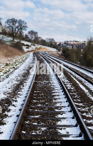 La neige a couvert des rails de chemin de fer à travers un paysage rural. Banque D'Images