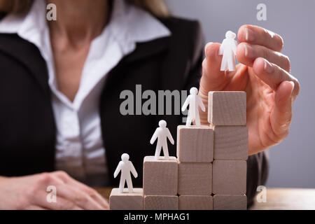 Main de l'homme d'affaires au placement des chiffres sur l'Escalier composé de blocs de bois Banque D'Images