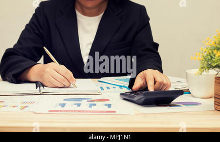 Businesswoman poussant et agissant sur la calculatrice et à la recherche d'affaires sur papier, concept finance sur table Banque D'Images