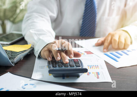 Businessman pushing et agissant sur la calculatrice et à la recherche d'affaires sur papier, sur la table de travail concept finance Banque D'Images