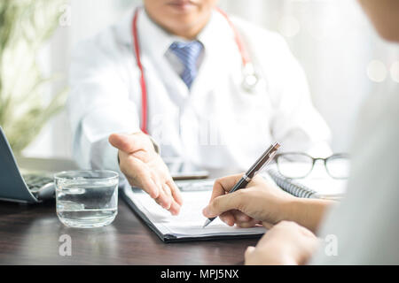 Signature du patient médecin introduit sur les dossiers médicaux avant de traiter la maladie à l'hôpital sur la table Banque D'Images