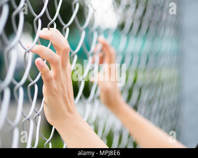 Les femmes Hands holding clôture sur un paysage extérieur en plein jour. Part en prison, concept de la prison à vie Banque D'Images