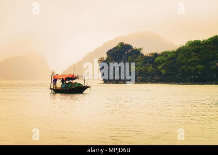 Bateau de pêche à la baie d'Ha Long, Vietnam au coucher du soleil. Îles de calcaire sur l'arrière-plan Banque D'Images