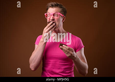 Beau jeune homme portant des lunettes et chemise rose contre bro Banque D'Images