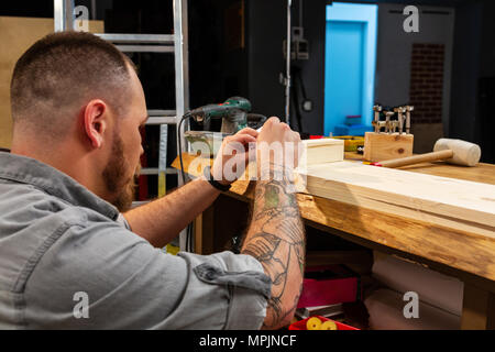 Portrait de la main d'un artisan qualifié couper une planche en bois avec une scie circulaire dans un atelier Banque D'Images