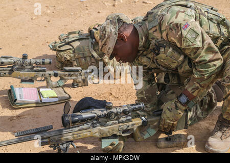 Un formateur britanniques déployées à l'appui de la Force opérationnelle interarmées - Fonctionnement résoudre inhérent et affecté à l'Highlanders, 4e Bataillon, The Royal Regiment of Scotland (4) charge un Écossais dans son magazine L115A3 fusil de sniper à longue portée pendant la formation à Al Asad Air Base, l'Iraq, le 21 mars 2017. Cette formation fait partie de l'ensemble de la CJTF OIR - renforcer les capacités des partenaires mission par la formation et de l'amélioration de la capacité des forces des combats en partenariat avec ISIS. Les GFIM - OIR est la Coalition mondiale pour vaincre ISIS en Iraq et en Syrie. (U.S. Photo de l'armée par le Sgt. Lisa soja) Banque D'Images