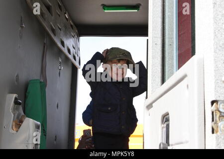 Un enfant de la Victoria Education Centre, Constanta trouve un bouchon de patrouille à l'arrière d'un camion de pompiers appartenant à un soldat du 359e détachement du génie pompiers de Fort Riley, Kansas lors d'une célébration de la Journée de l'enfance à l'aéroport Mihail Kogalniceanu, le 24 mars 2017. L'événement a été une occasion pour les enfants d'obtenir un examen attentif des soldats américains dans leur pays. Dans le cadre de l'opération Atlantic résoudre, la mission de l'OTAN impliquant les États-Unis et leurs alliés et partenaires européens constitue un effort pour renforcer les liens et de dissuader l'agression en Europe. L'événement a donné un troupes cha Banque D'Images