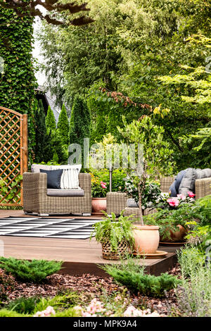 Belle terrasse avec jardin Fauteuil, tapis à motifs, entouré par des arbres et des plantes Banque D'Images