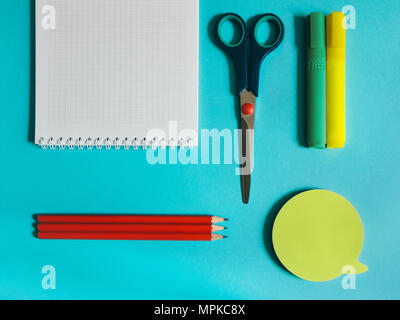 Ordinateur portable photo fournitures scolaires, papeterie, des ciseaux, des crayons et marqueurs autocollants sont allongés sur le bureau bleu Banque D'Images