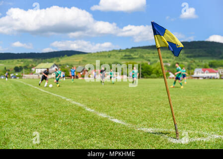 Retro poteau de corner au premier plan sur le terrain de soccer amateur, les joueurs de football lutte pour la balle de l'arrière-plan flou Banque D'Images