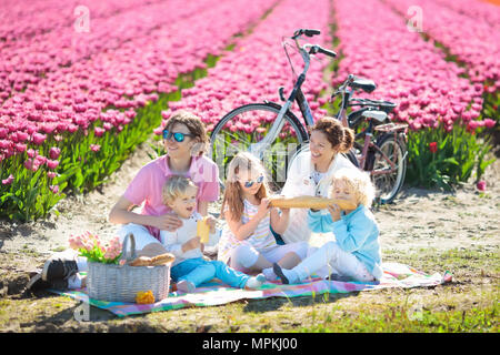 Pique-nique en famille à champs de fleurs tulipes en Hollande. Jeune mère et enfants de manger le déjeuner dans blooming tulipes fleur champ. Maman et les enfants voyagent en vélo. Banque D'Images