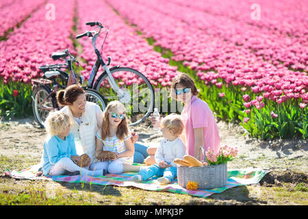 Pique-nique en famille à champs de fleurs tulipes en Hollande. Jeune mère et enfants de manger le déjeuner dans blooming tulipes fleur champ. Maman et les enfants voyagent en vélo. Banque D'Images