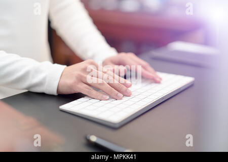 Conseiller financier de taper au clavier tout en étant assis au bureau et de travail sur ordinateur - filtre appliqué Banque D'Images