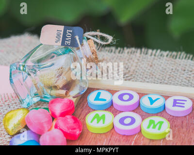 Maman amour écrit avec l'alphabet coloré de blocs et un cœur rouge isolé sur planche de bois et sack - Fête des Mères Banque D'Images