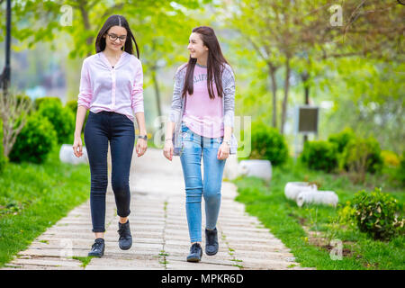 Deux jolies soeurs filles marcher et s'amuser ensemble dans le parc au printemps. Banque D'Images