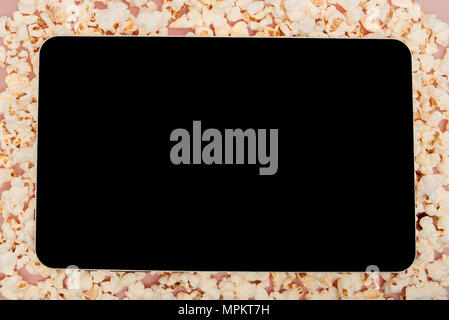 Popcorn with digital tablet sur fond rose. Banque D'Images