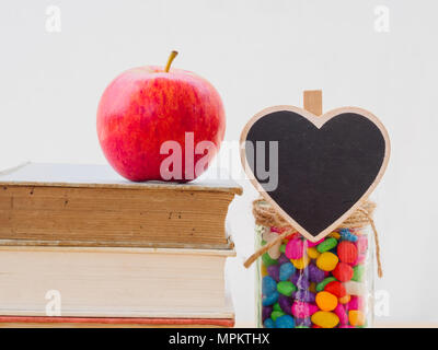 Concept de la Journée mondiale du livre. Pomme Rouge mis sur de vieux livres avec coeur noir et coloré de stons in jar Banque D'Images
