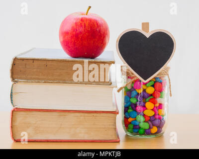 Concept de la Journée mondiale du livre. Pomme Rouge mis sur de vieux livres avec coeur noir et coloré de stons in jar Banque D'Images