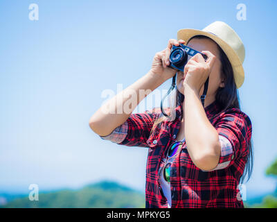 Portrait de vie extérieure d'été jolie jeune femme ayant l'amusement dans la jungle. Faire des photos photographe en style hippie lunettes et chapeau. Banque D'Images