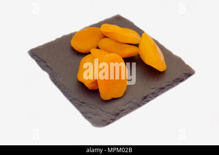 Abricots dénoyautées sur ardoise Plaque sur fond blanc vue rapprochée Banque D'Images