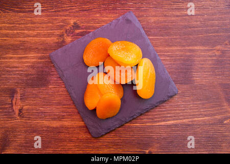 Abricots dénoyautées sur ardoise plateau sur une table en bois vu de dessus Banque D'Images