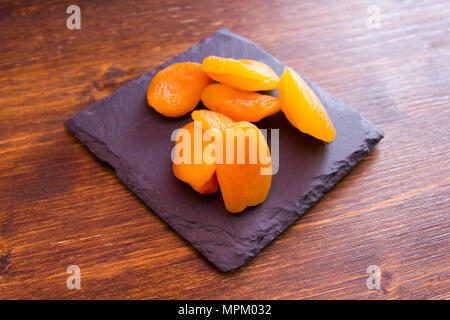 Abricots dénoyautées sur ardoise plateau sur une table en bois vu close up Banque D'Images