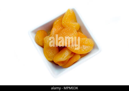 Abricots dénoyautées sur un bol carré sur un fond blanc (vue de dessus Banque D'Images