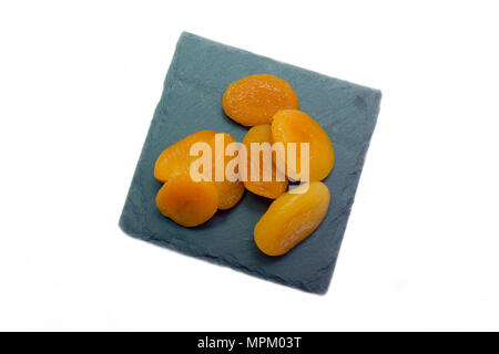 Abricots dénoyautées sur ardoise plateau sur un fond blanc (vue de dessus Banque D'Images
