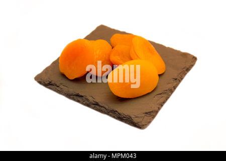 Abricots dénoyautées sur ardoise Plaque sur fond blanc Banque D'Images