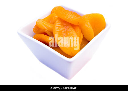 Abricots dénoyautées sur un bol carré sur fond blanc vue rapprochée Banque D'Images