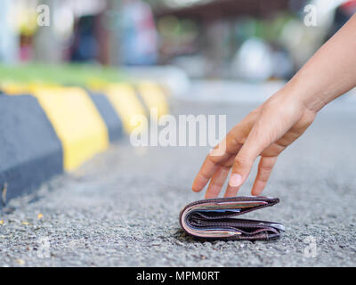 Close-up of a Woman Picking Up porte-monnaie tombé sur le côté de la route Banque D'Images