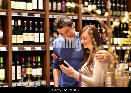 Jeune couple chanceux pour le vin dans le supermarché Banque D'Images